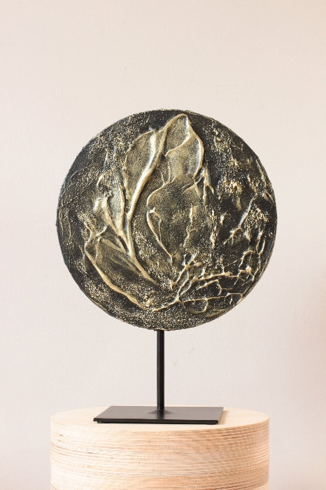 Black and gold abstract painting on a sculpure pedestal.