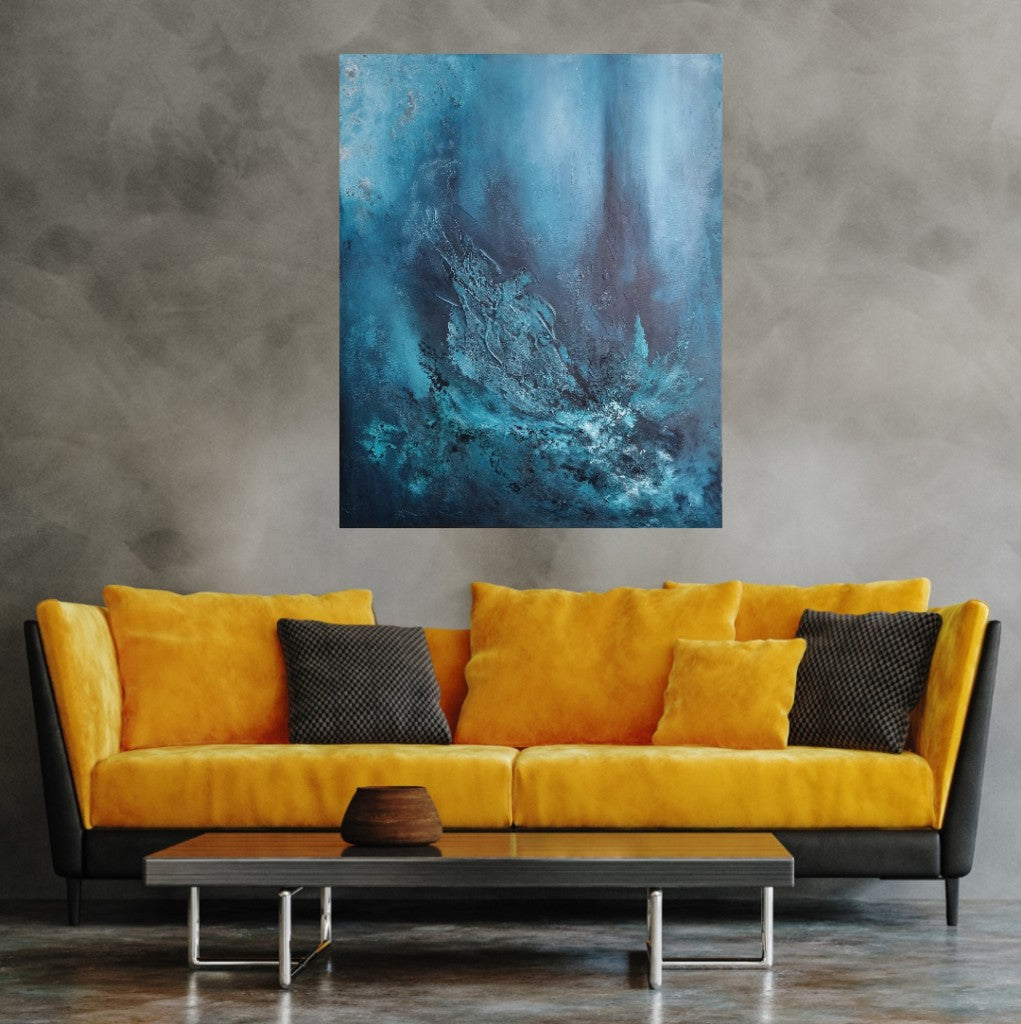 An abstract painting on a gray wall above a yellow sofa in a modern living room setting. The painting features various shades of blue with texture paste, created using acrylic paint on canvas.