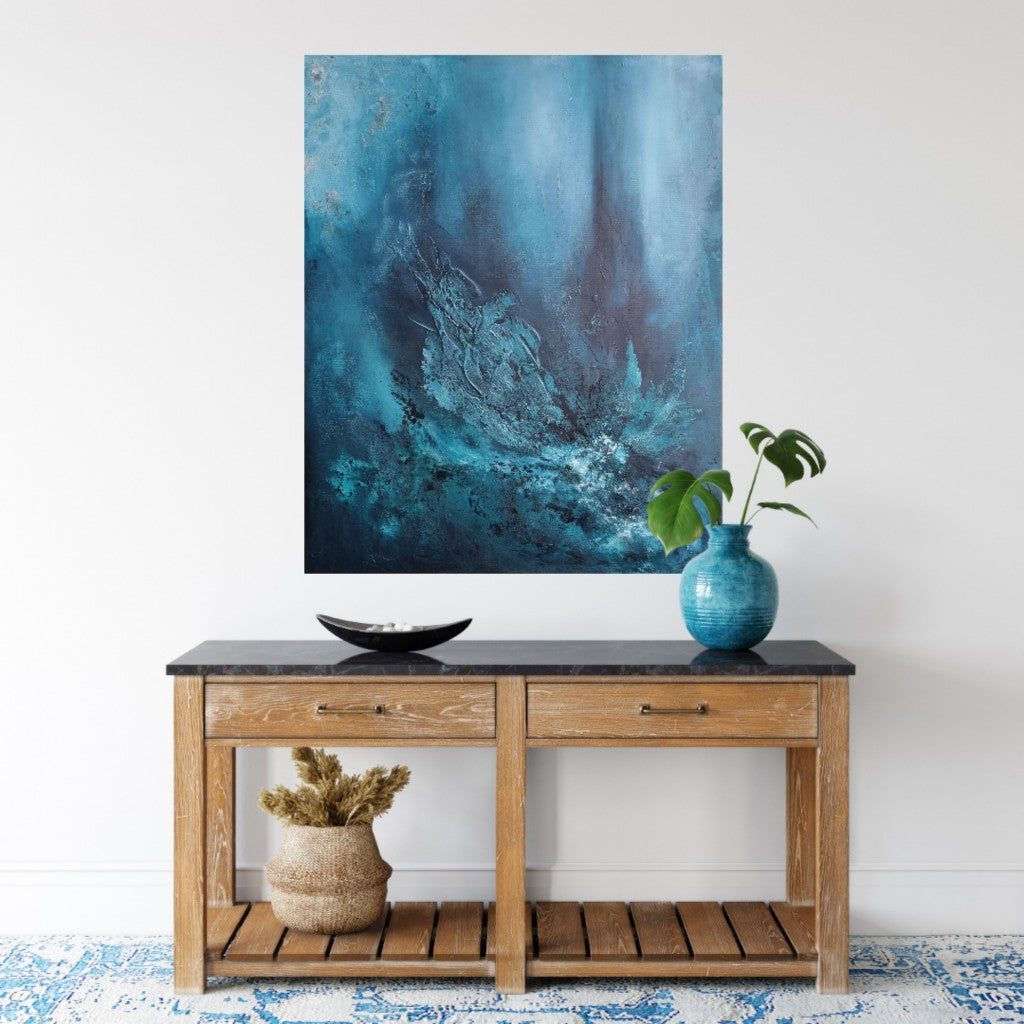 Large abstract painting with texture and shades of blue, green and petrol above a wooden sideboard.