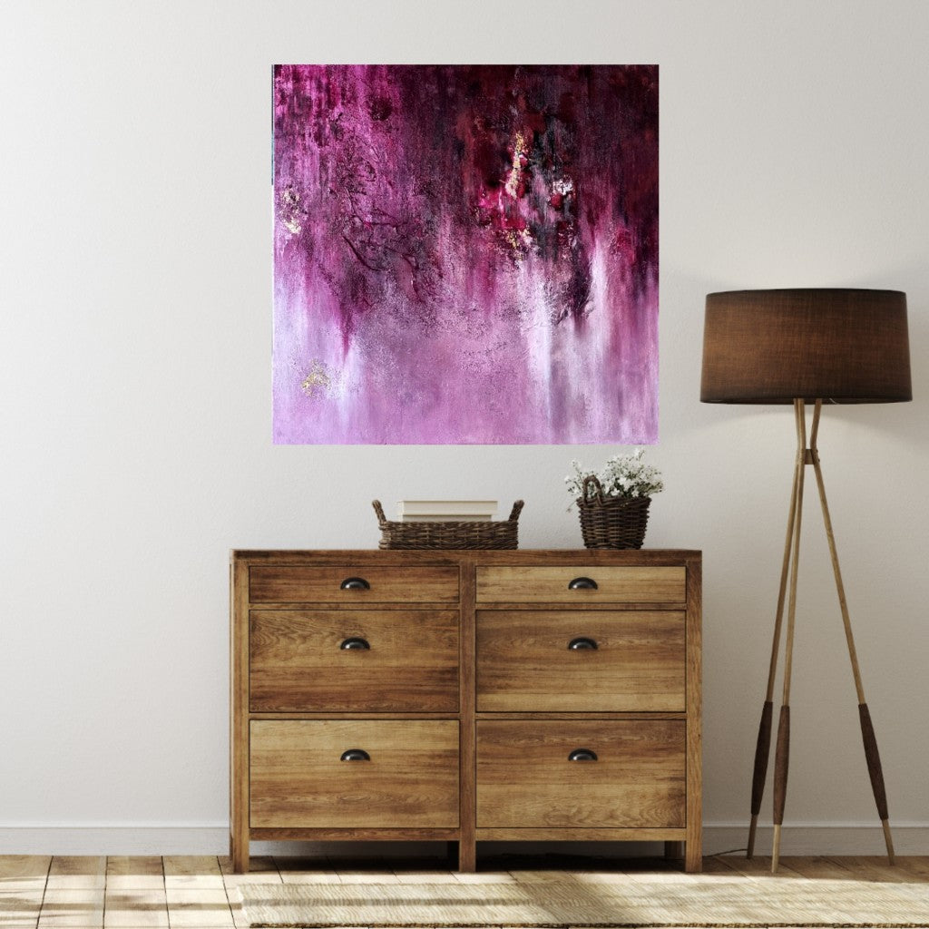 An abstract pink painting above a wooden sideboard. 